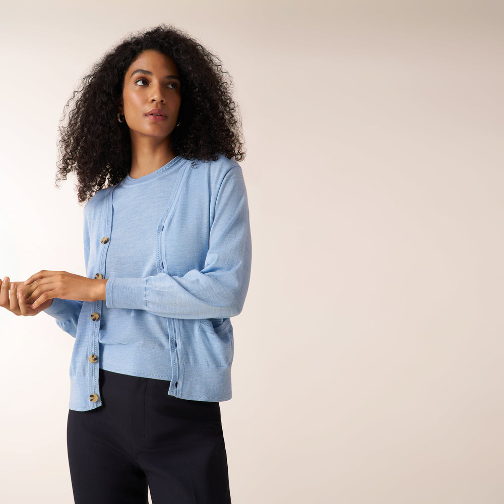 Woman wearing alight blue short sleeve sweater tank with a matching cardigan and wide leg white jeans
