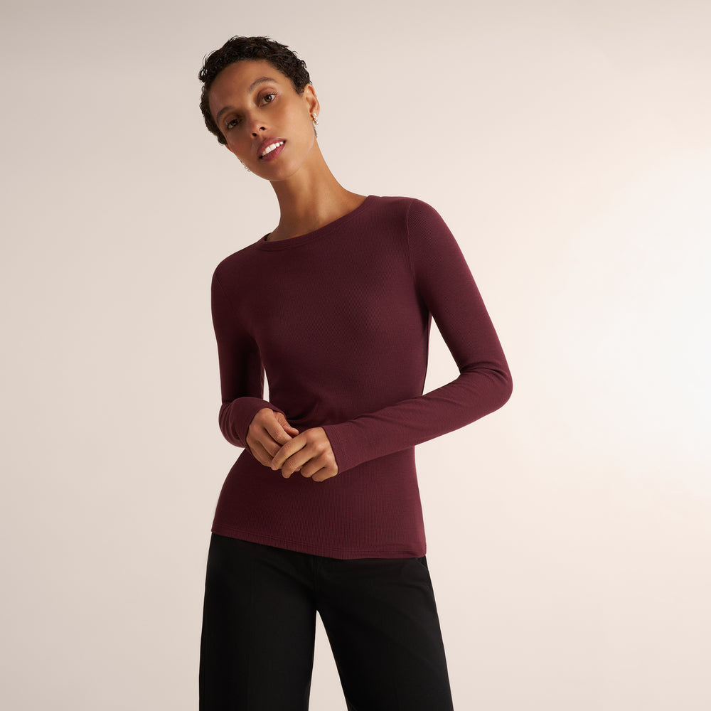 Woman wearing a long sleeve aubergine ribbed t-shirt with black pants