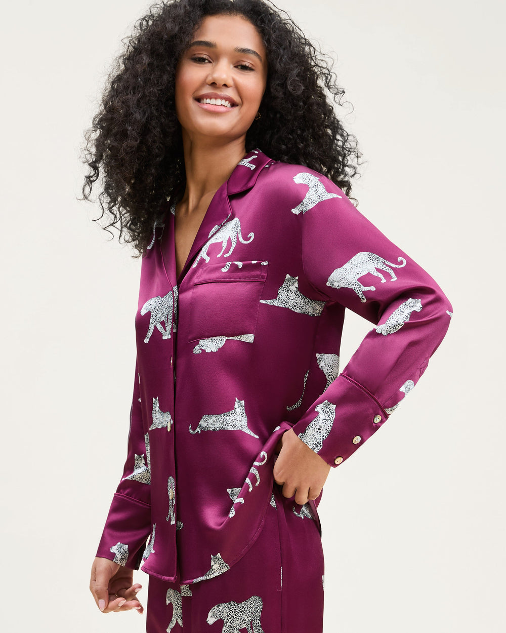 Woman wearing a purple pajama set with animal patterns on a plain background