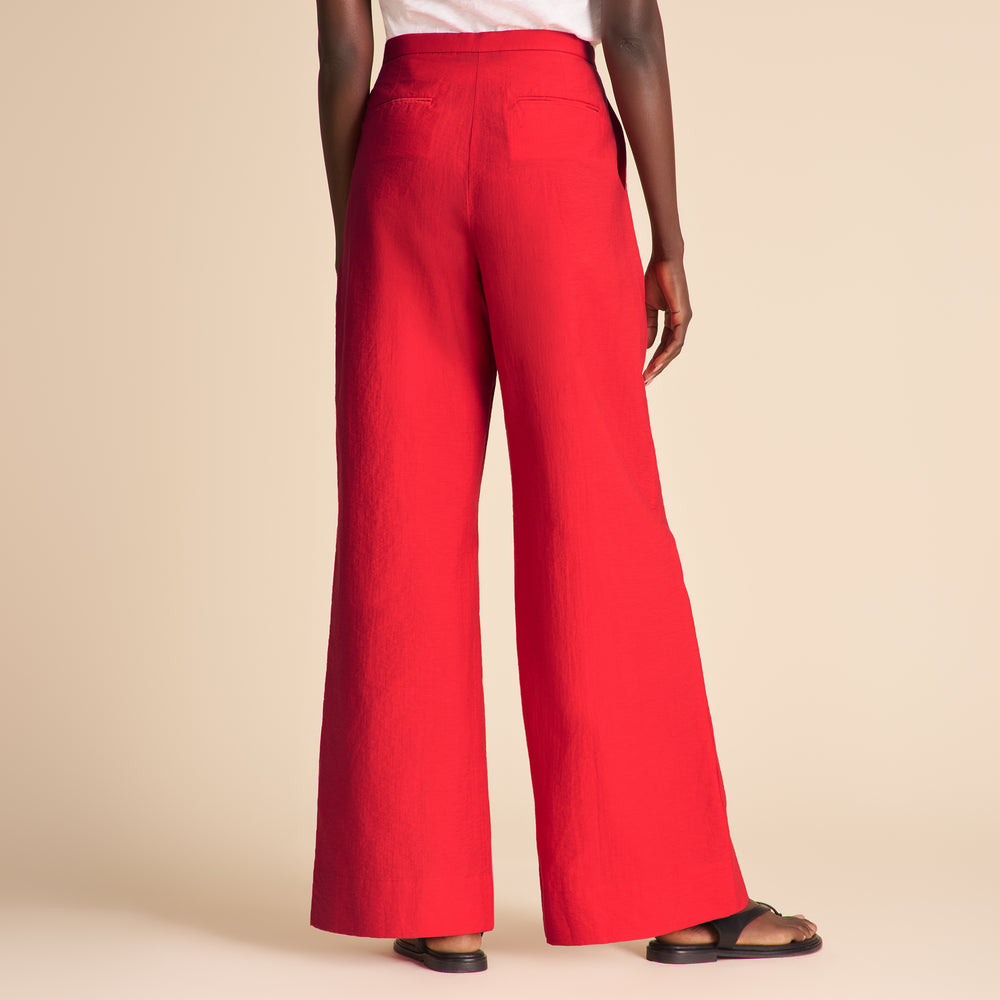 Woman wearing red pants on a beige background.