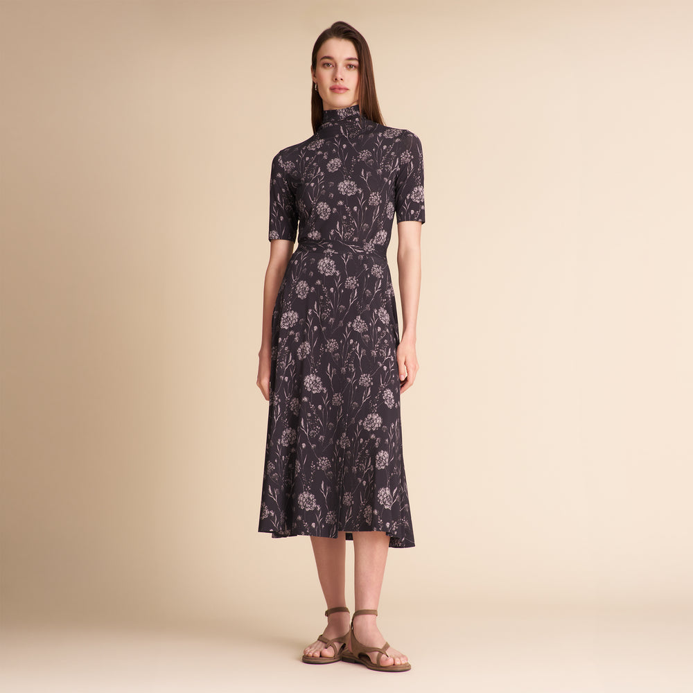 Woman wearing a dark floral matching top and skirt on a beige background