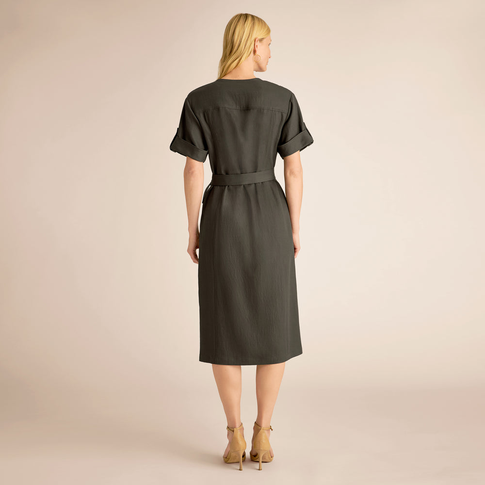 Woman wearing a green dress with a belt on a beige background