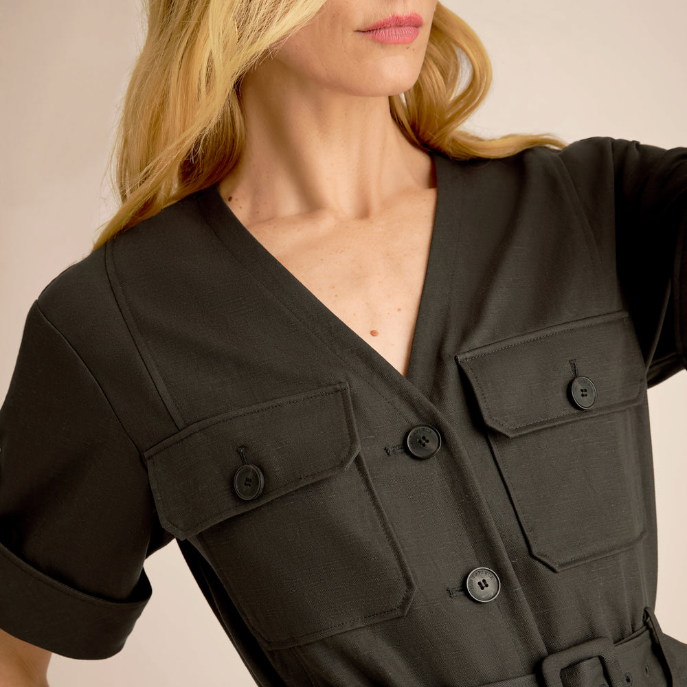 Woman wearing a black jacket with pocket details on a beige background