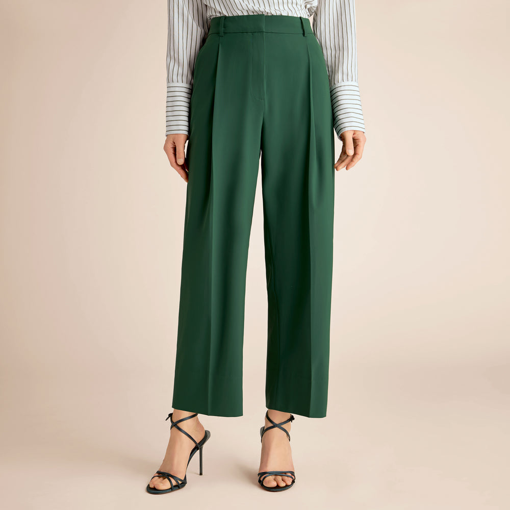 Green pants worn with a striped shirt on a beige background
