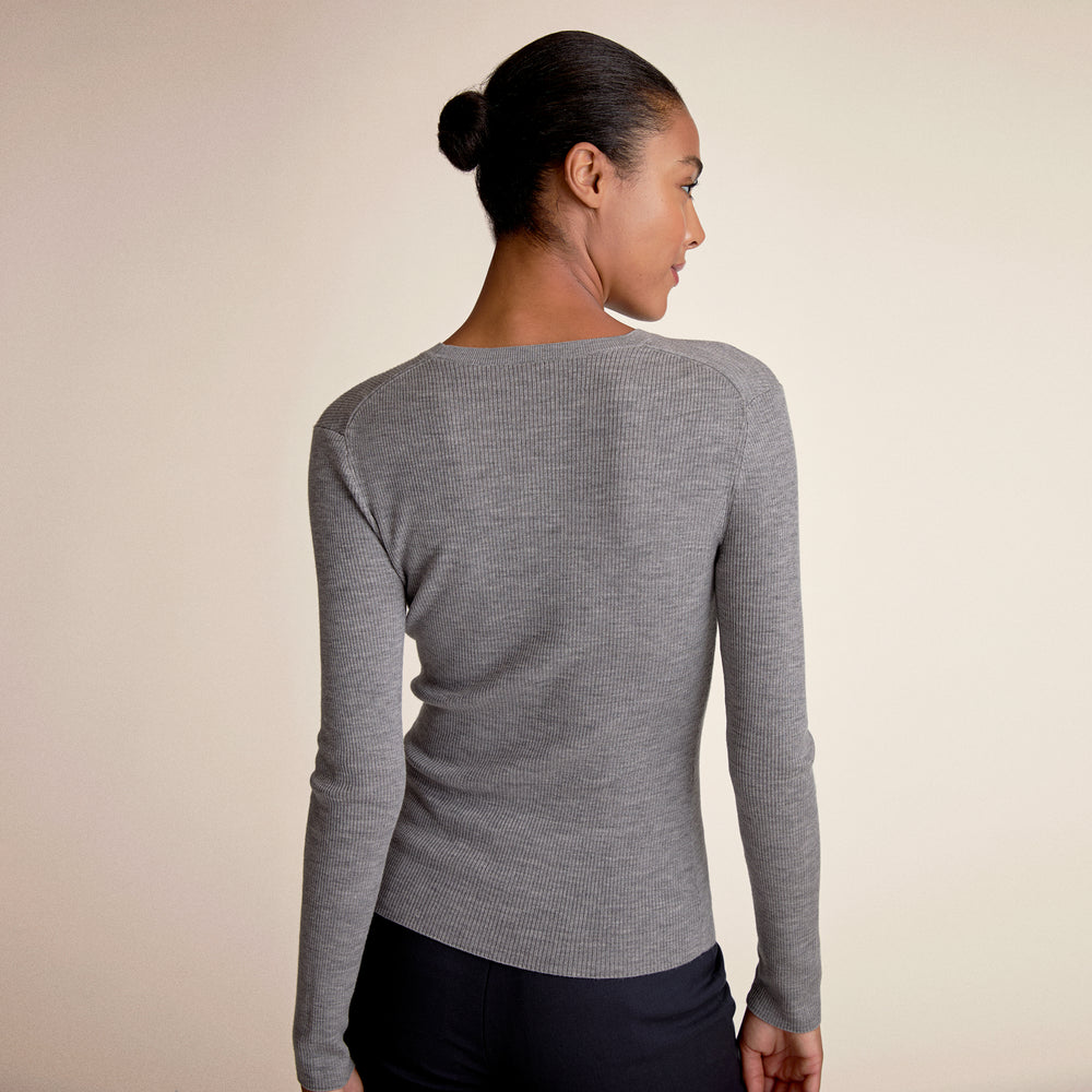 Woman wearing a gray long-sleeve top against a beige background