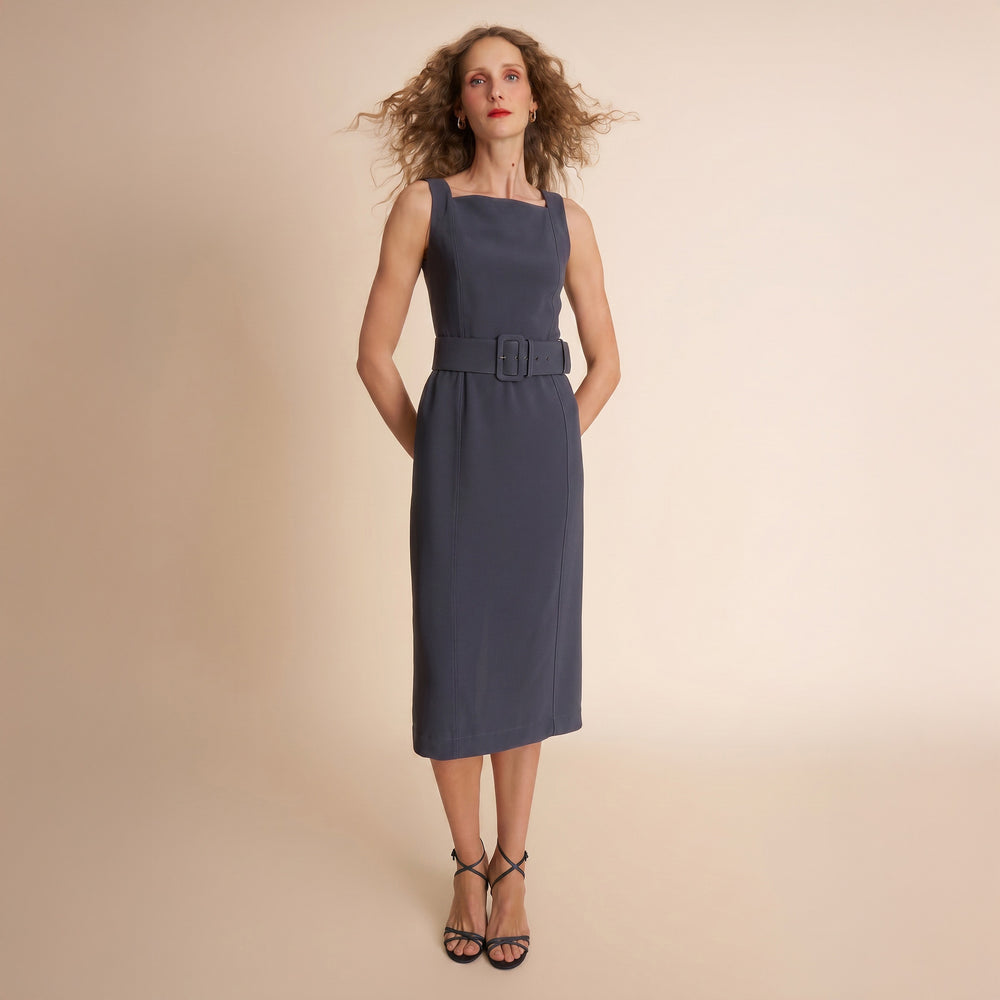 Woman wearing a navy blue dress with a belt on a beige background