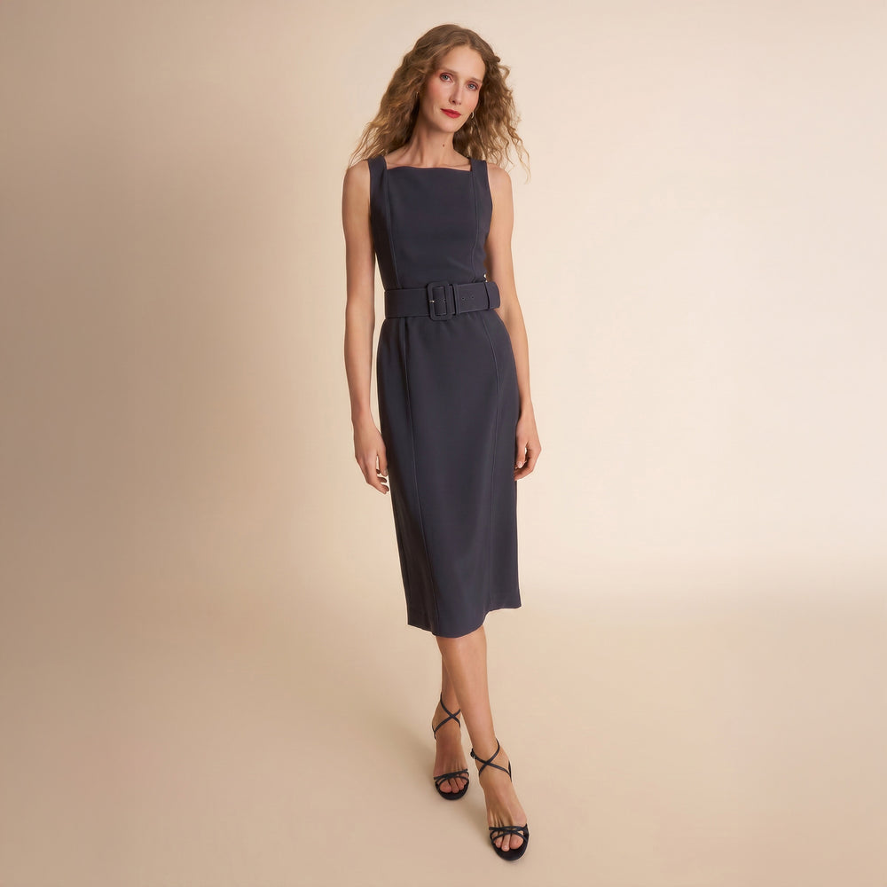 Woman wearing a navy dress with a belt on a beige background