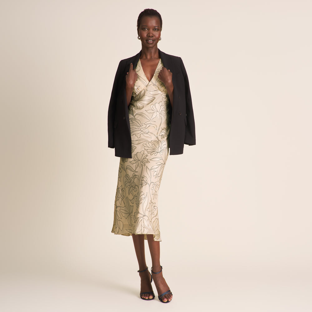 Woman wearing a black jacket over a floral dress on a beige background