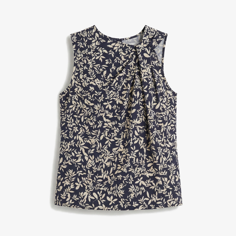 A sleeveless top with a tie-neck detail, featuring an all-over beige leaf print on a navy blue background, shown flat against a light gray background.