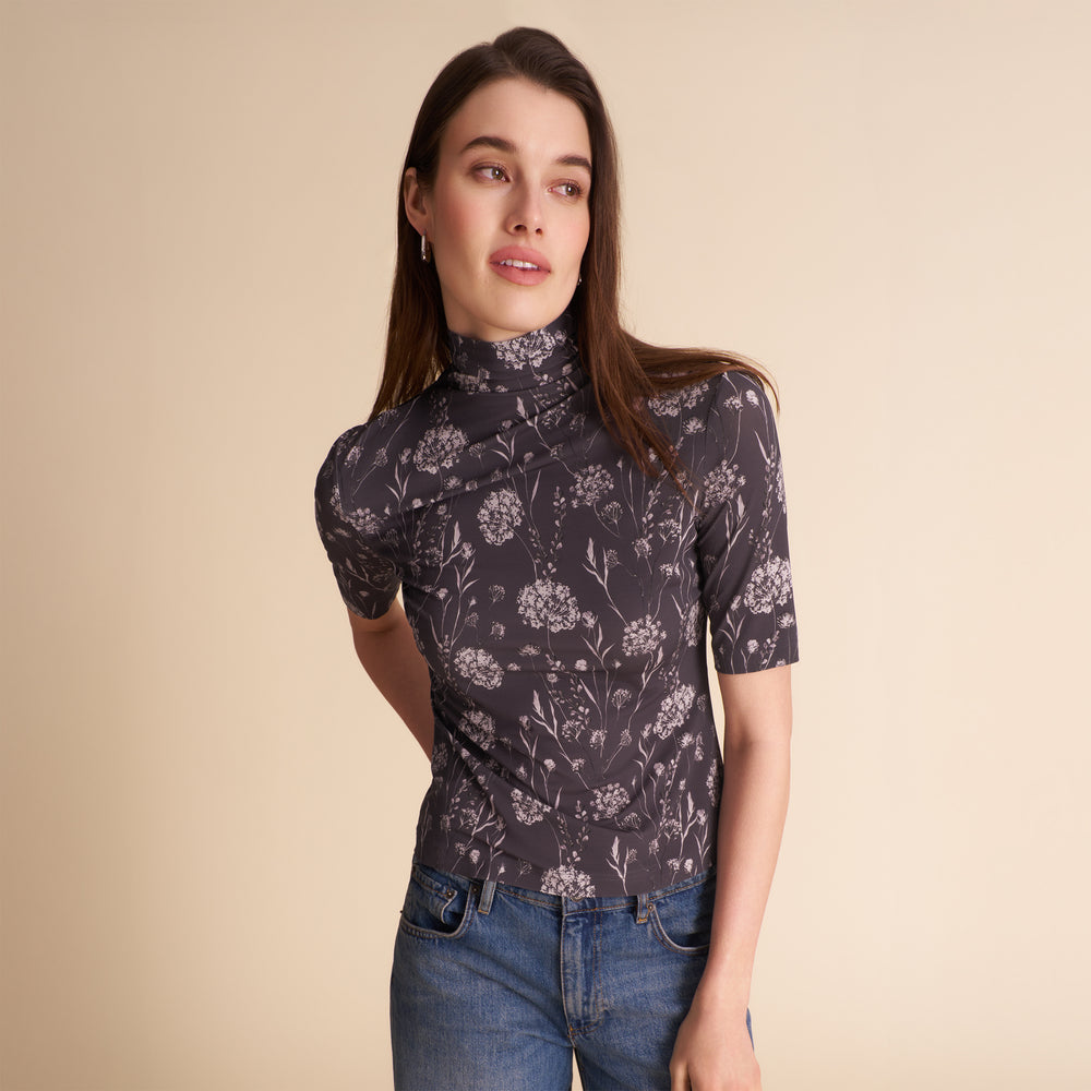 Woman wearing a patterned top and jeans on a beige background