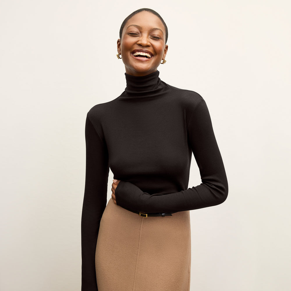 Front image of a woman standing wearing the axam top in black