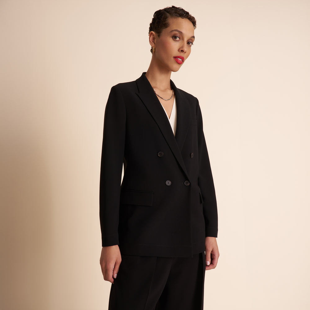 Woman wearing a black suit against a beige background