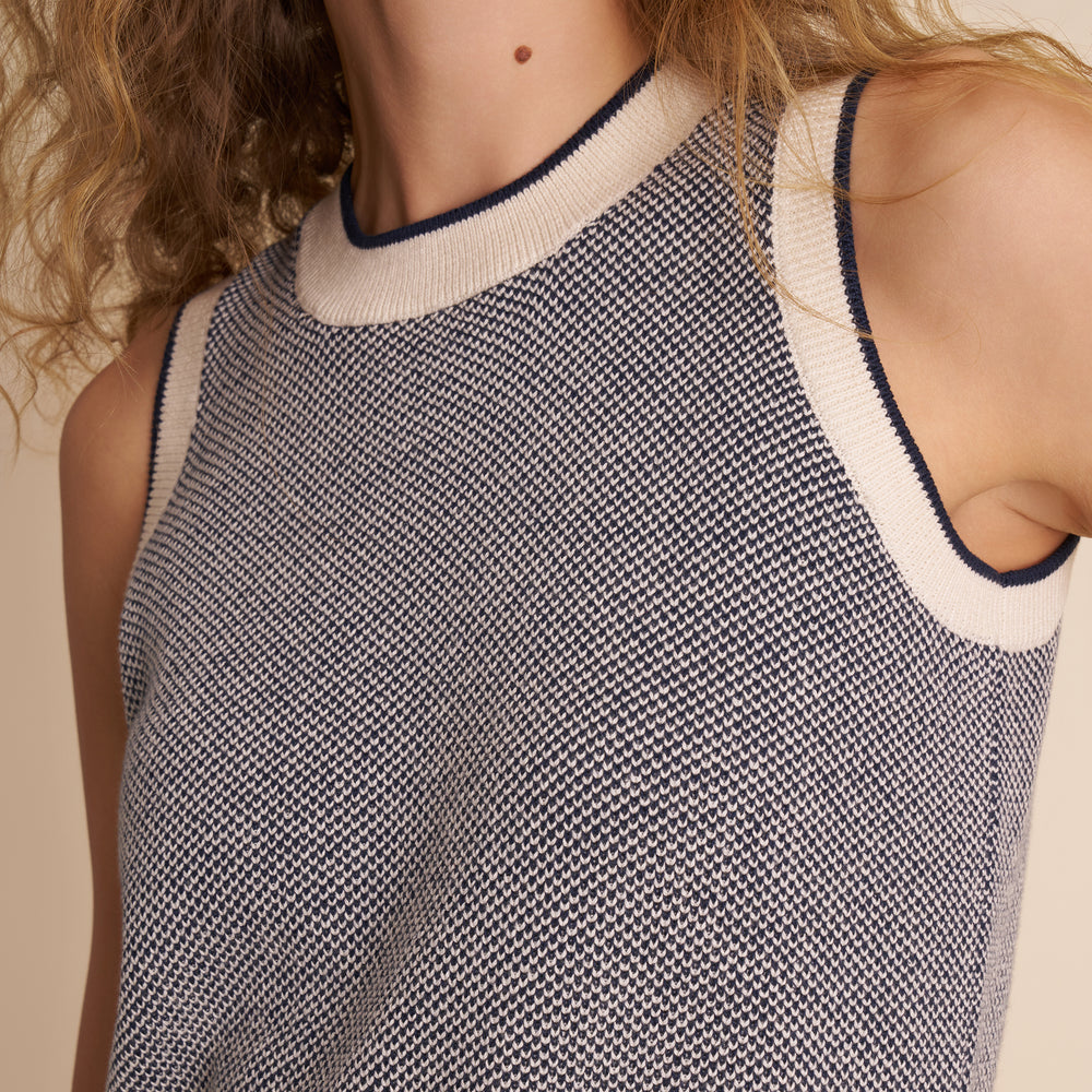 Close-up of a sleeveless knitted top with a textured pattern on a neutral background