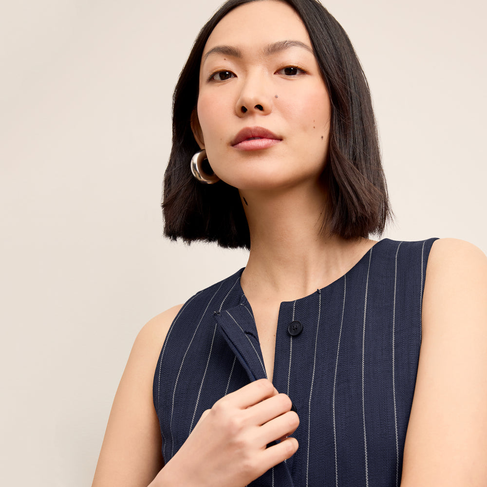 Woman wearing a navy pinstripe dress against a beige background
