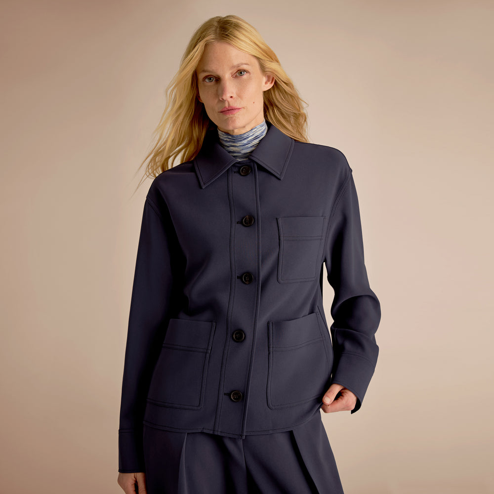 Woman wearing a navy blue coat with a beige background
