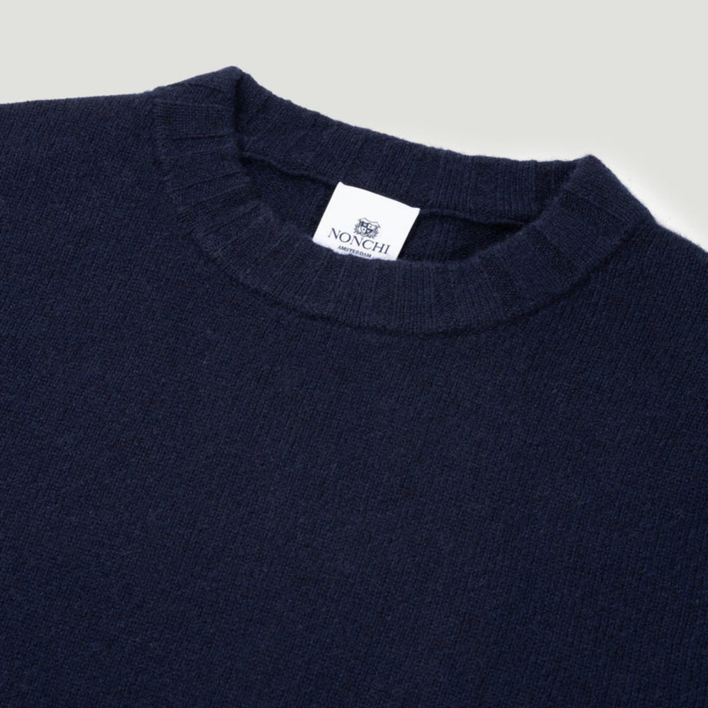 Navy sweater with a visible brand label on a light gray background