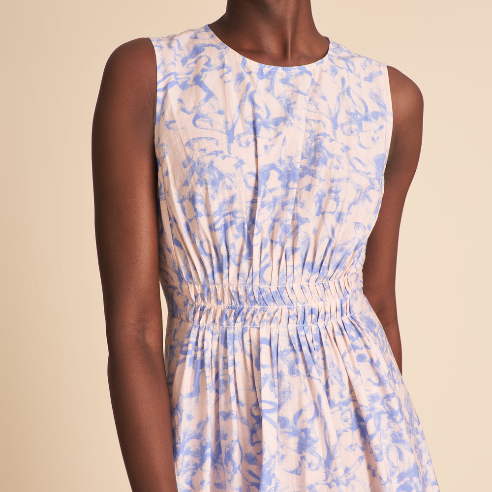 Woman wearing a sleeveless dress with blue and beige abstract pattern on a beige background