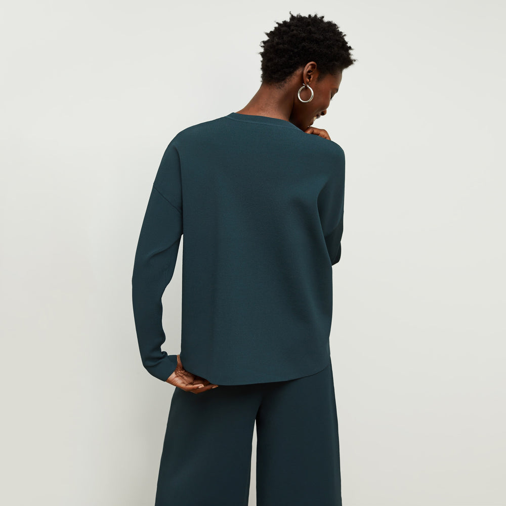 Back image of a woman standing wearing the para pullover in deep sea