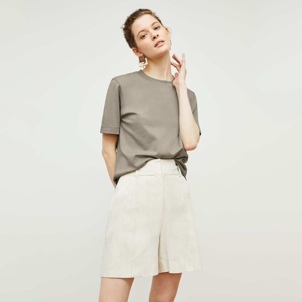 Front image of a woman standing wearing the Leslie T-Shirt—Compact Cotton in Pebble