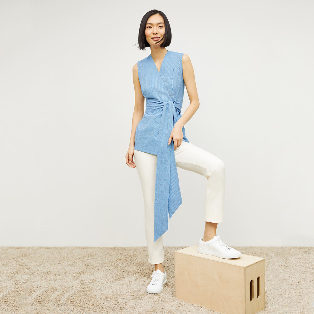 Front image of a woman standing wearing the ellen top in gingham seersucker in capri blue and white