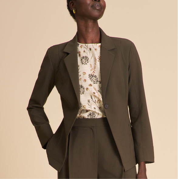 Woman wearing a brown suit with a floral blouse on a beige background
