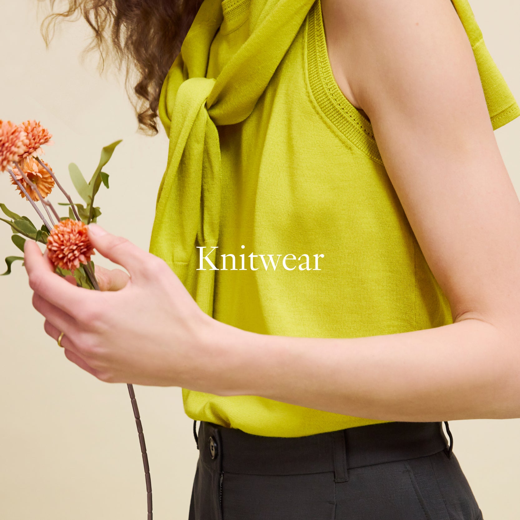 Person wearing a green knit top holding flowers with 'Knitwear' text on a beige background