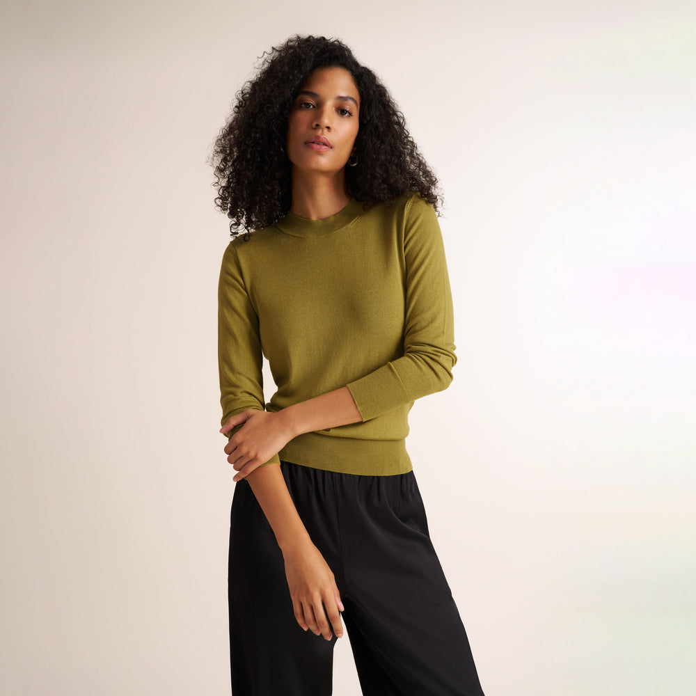Woman wearing an olive green color long sleeve sweater with black wide leg pants