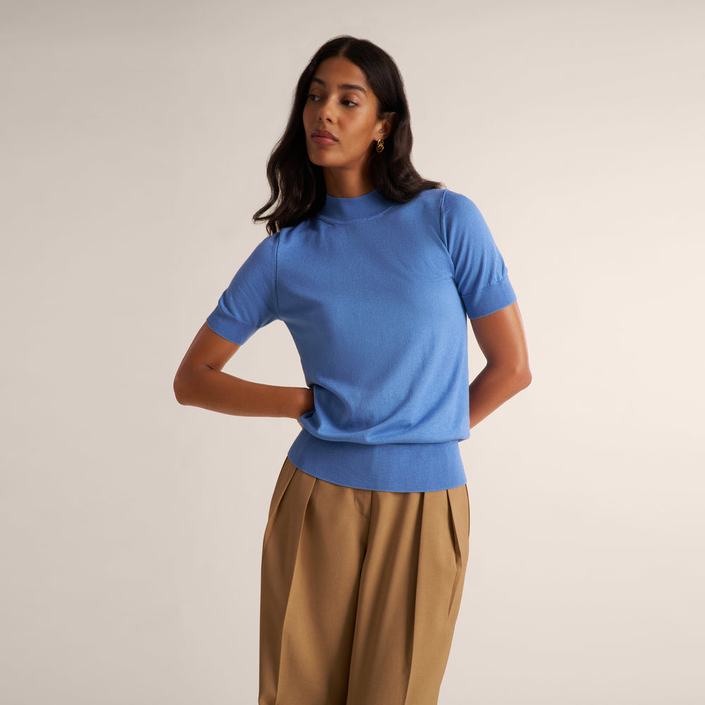 Woman wearing a blue splendor color short sleeve sweater with beige wide leg pants