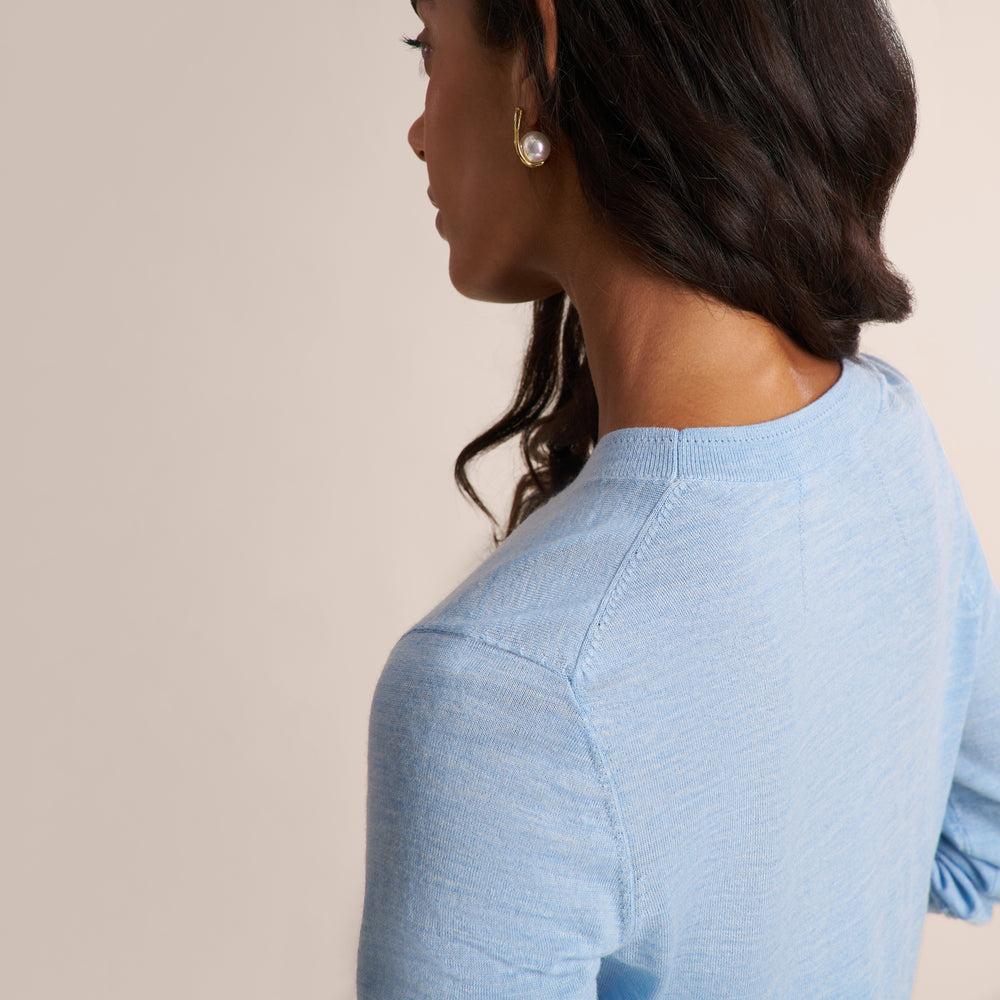 Woman wearing a light blue long sleeve sweater with dark gray herringbone pants