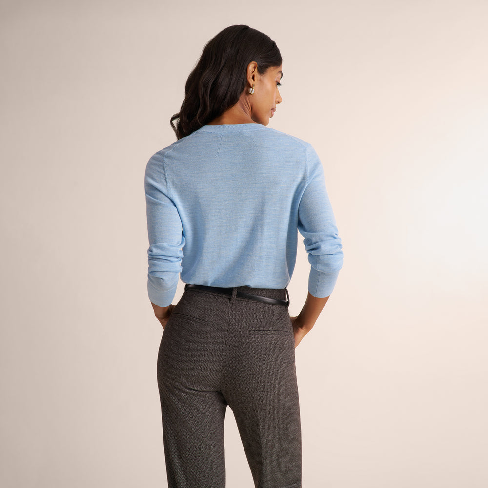 Woman wearing a light blue long sleeve sweater with dark gray herringbone pants