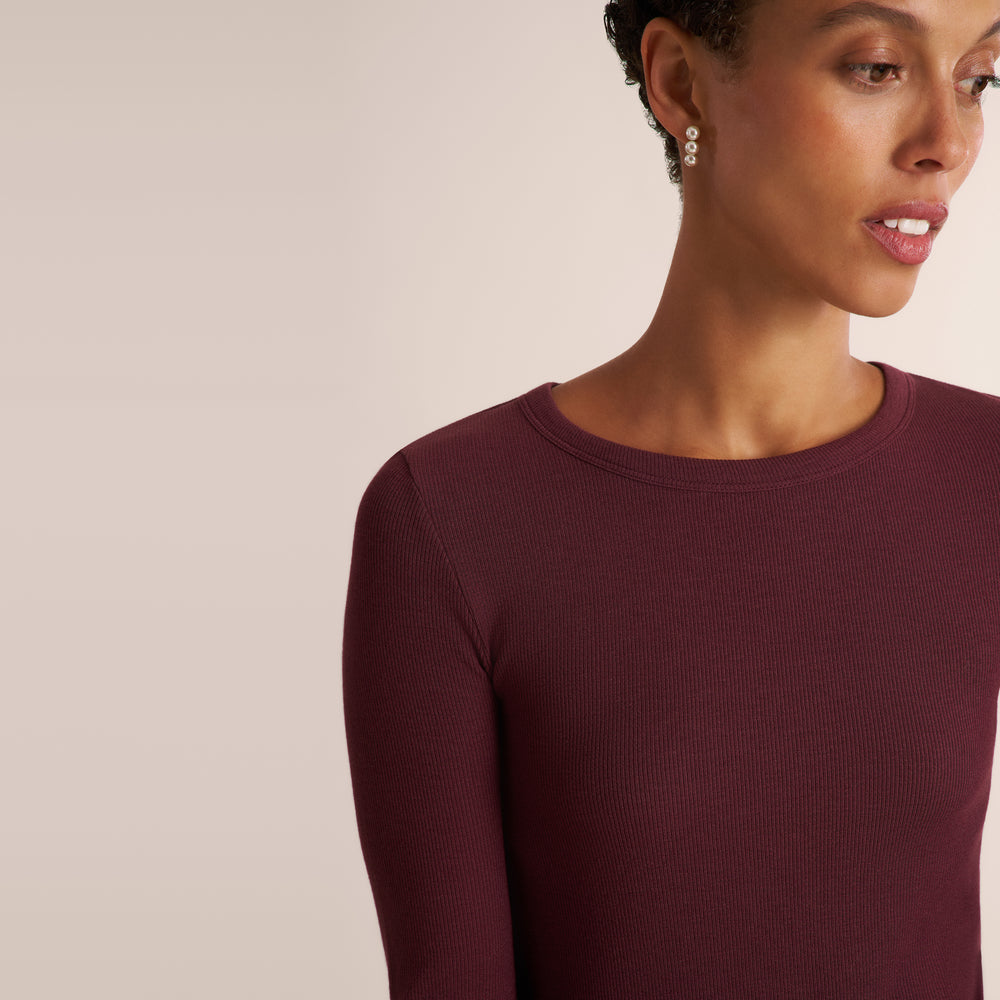 Woman wearing a long sleeve aubergine ribbed t-shirt with black pants