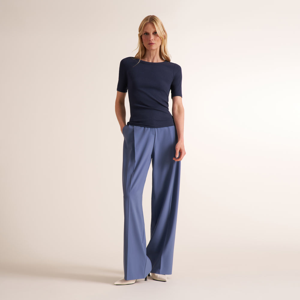 Woman wearing a navy crew neck, short sleeve t-shirt with blue trouser pants