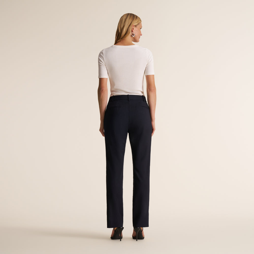 back image of a woman sitting wearing the smith pant in navy blue