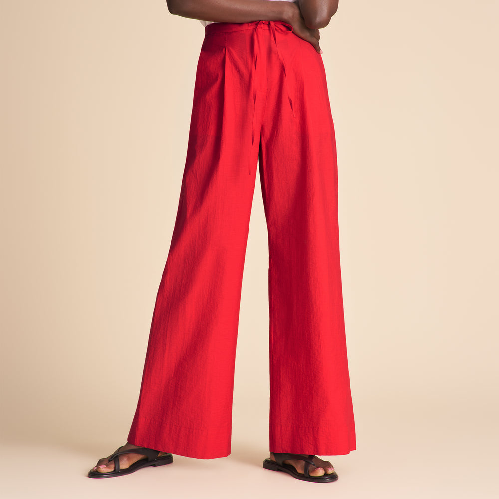 Woman wearing red pants on a beige background.