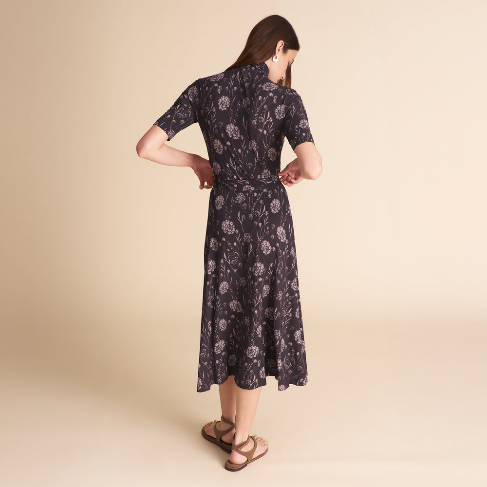 Woman wearing a dark floral matching top and skirt on a beige background