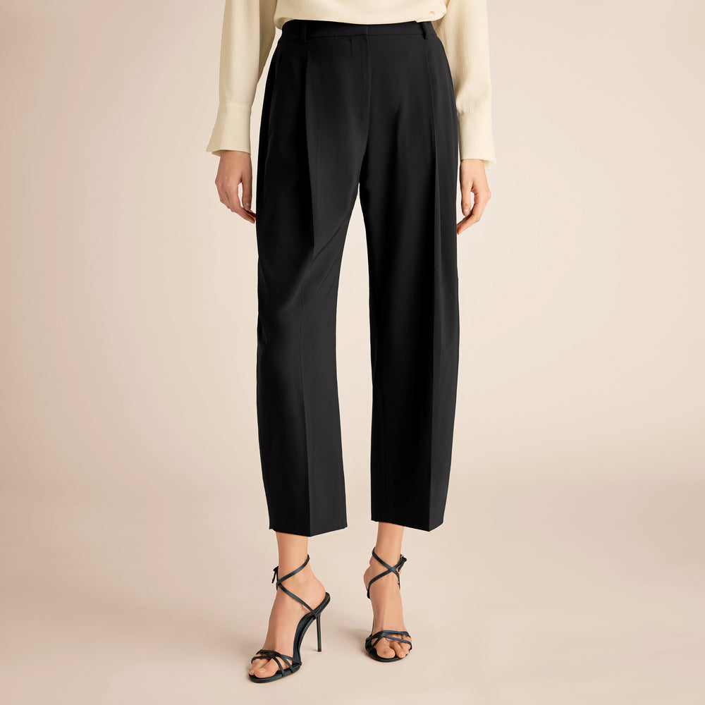 Black pants worn by a person on a beige background