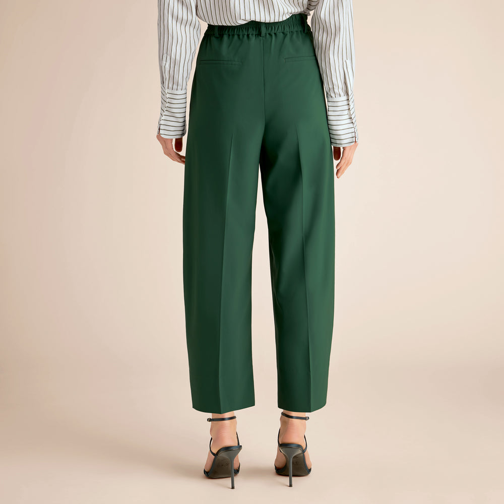 Green pants worn by a person on a beige background