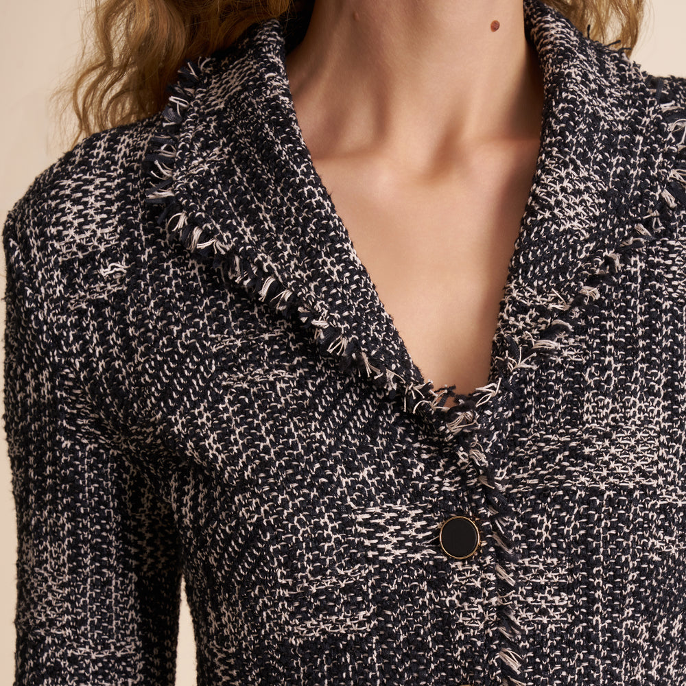 Close-up of a textured black and white jacket with a button detail.