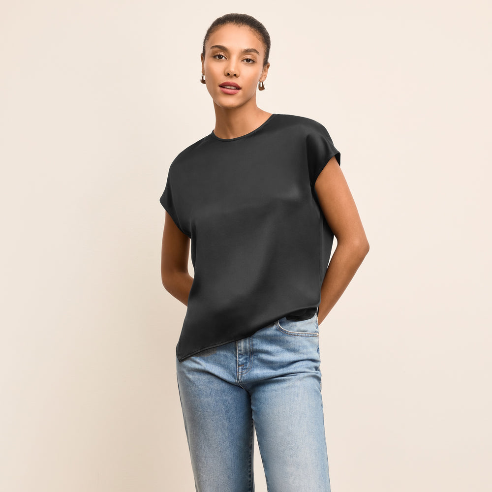Woman wearing a black top and blue jeans on a beige background