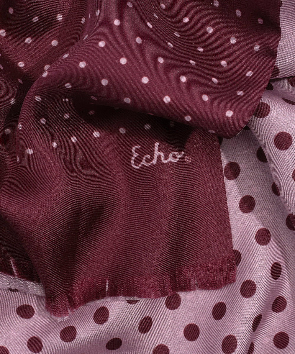 Close-up of a burgundy fabric with white polka dots and 'Echo' branding.