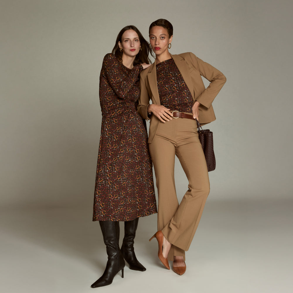 Two women in vintage-style clothing posing against a neutral background