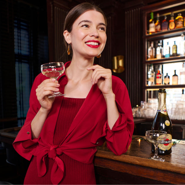 Woman in a red dress holding a glass of white wine in a bar setting