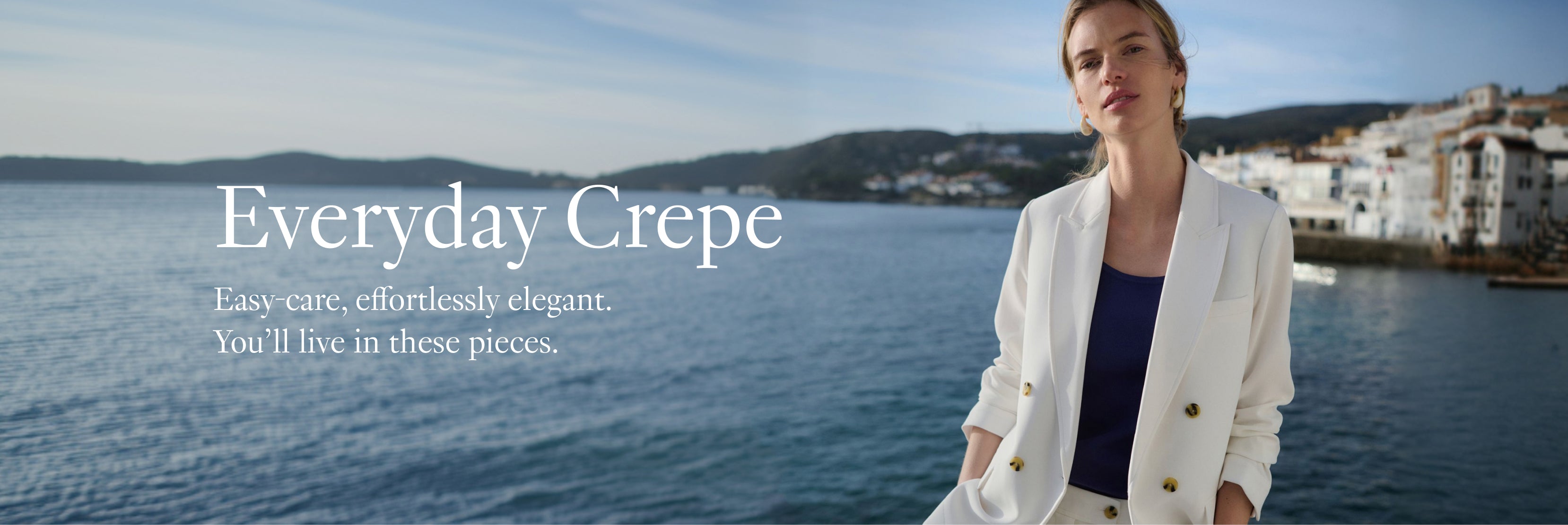 Woman in a white blazer standing by a waterfront with 'Everyday Crepe: Easy-care, effortlessly elegant. You'll live in these pieces."