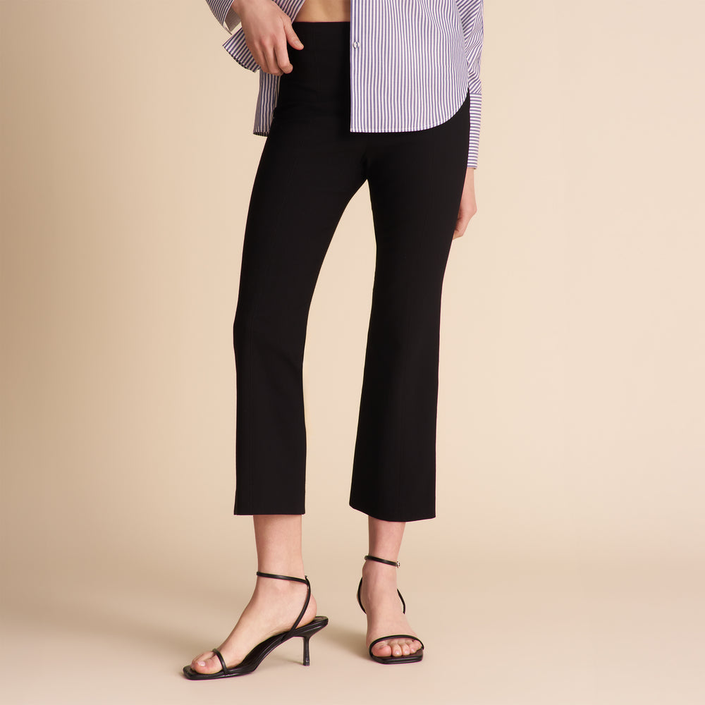 Person wearing black pants on a beige background