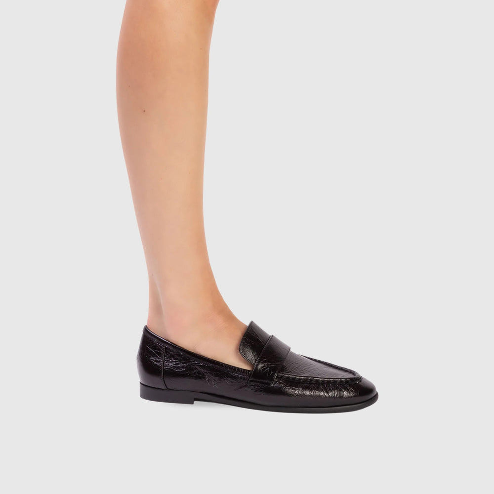 Black loafers worn by a person on a light gray background