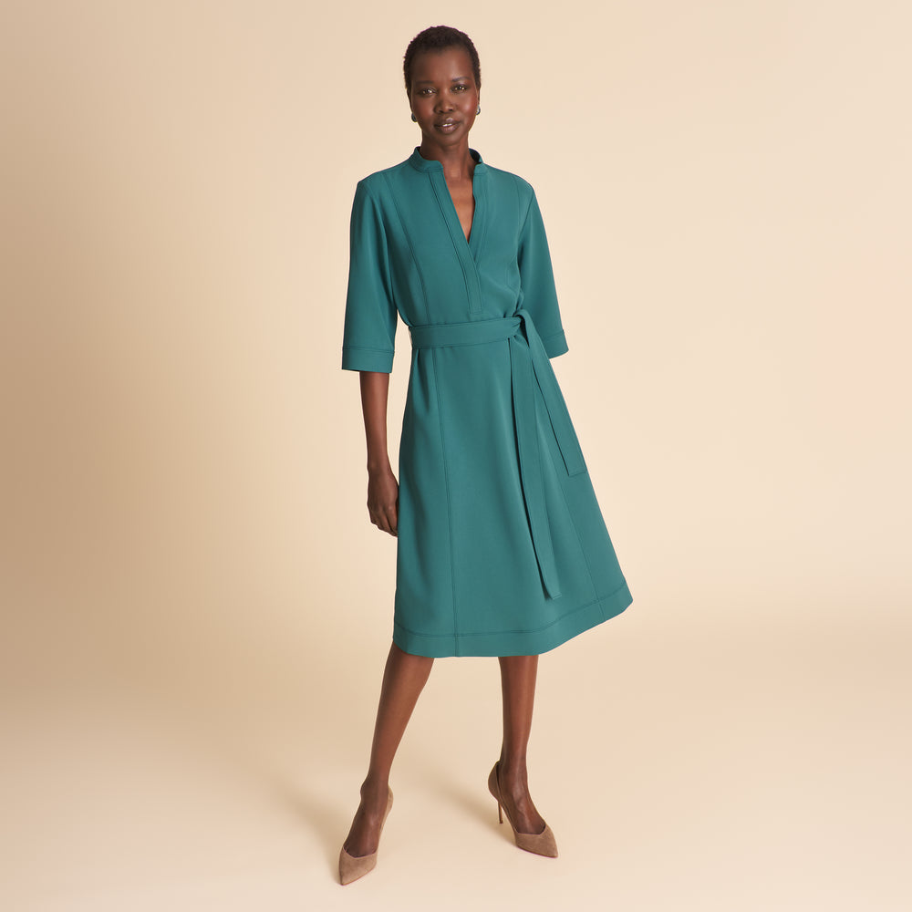 Woman wearing a teal dress on a beige background