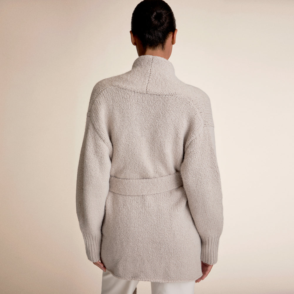 Woman wearing a light beige cardigan and white pants