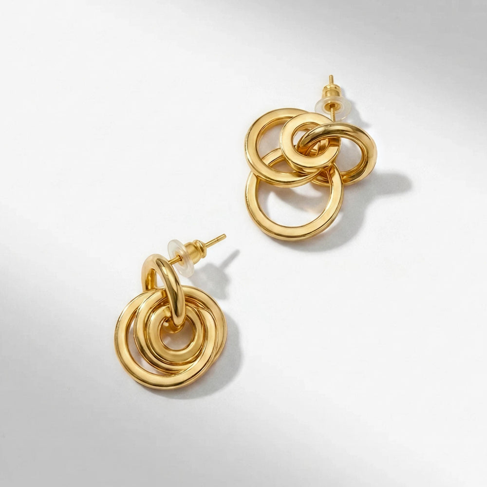 A pair of gold-toned drop earrings with three interlocking circular rings, shown on a clean white background with soft shadows.