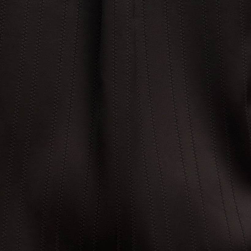 Person wearing a black satin shirt on a beige background