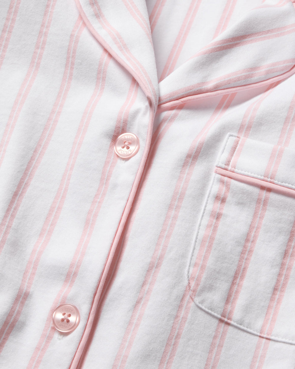 Close-up of a white shirt with pink stripes and buttons.